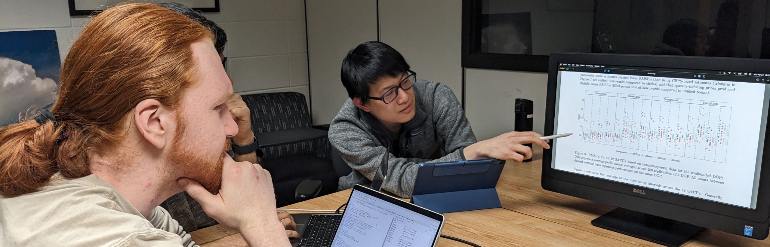 statistical consulting session, showing two researchers working collaboratively looking at a computer screen with data visualizations.