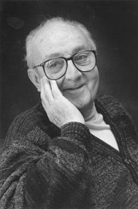 Black and white photo of man with glasses touching cheek